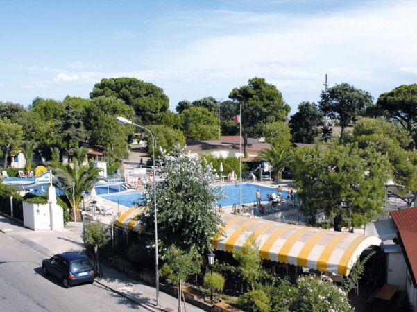 Piscina all'aperto circondata da alberi e strutture, vista dall'alto.