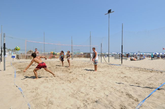 Persone che giocano a beach volley su una spiaggia sabbiosa.