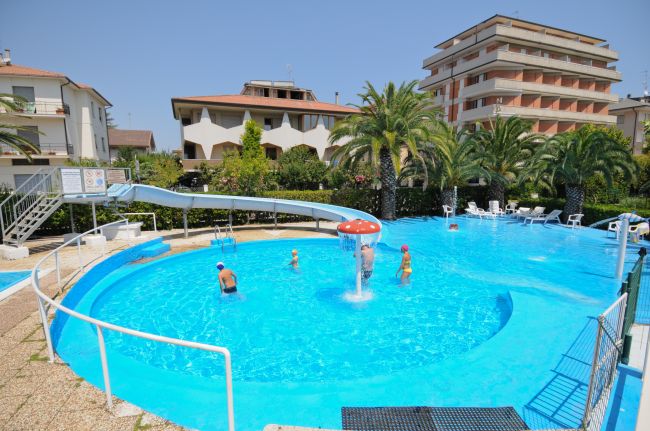 Piscina con scivolo e palme intorno.