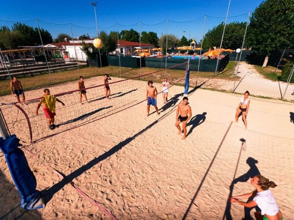 Persone giocano a beach volley su un campo sabbioso all'aperto.