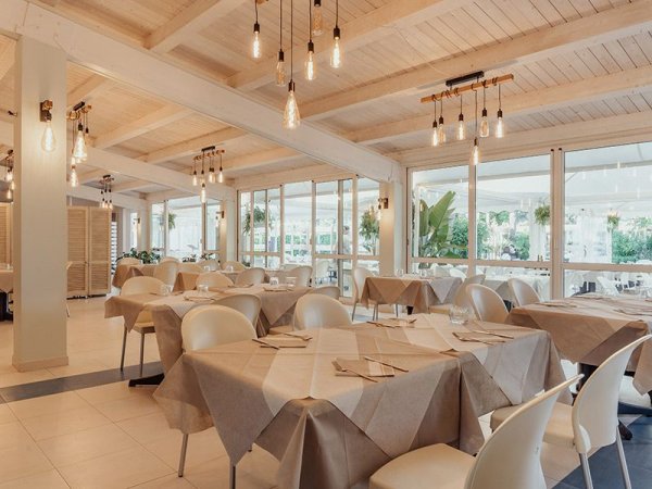 Ristorante elegante con tavoli apparecchiati e soffitto in legno.