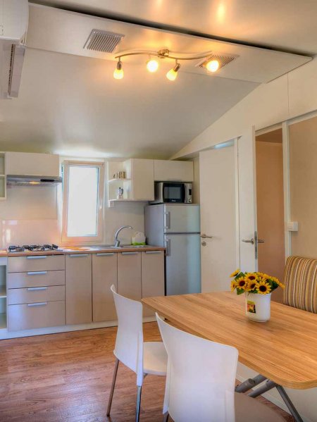 Cucina moderna con tavolo, sedie bianche e un vaso di girasoli.