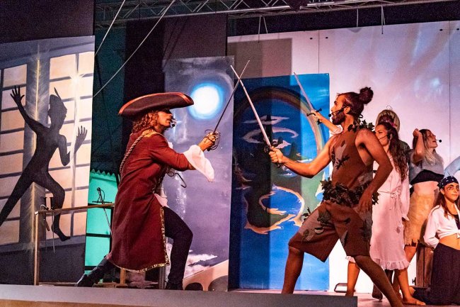 Due attori in costume da pirati si sfidano con spade su un palcoscenico.