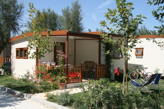 Bungalow in legno con piccolo giardino fiorito e veranda.
