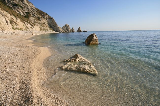 Spiaggia con rocce, acqua trasparente e scogliere.