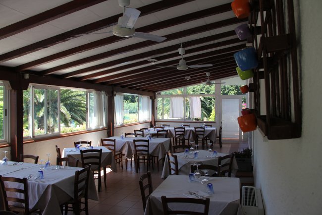 Interno di un ristorante con tavoli apparecchiati e vetrate luminose.