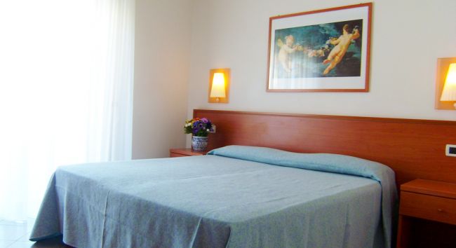 Camera da letto con letto matrimoniale, quadri e lampade a parete.