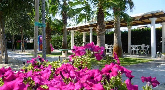 Giardino con fiori rosa vivaci e area ombreggiata.