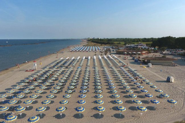 Una spiaggia con file ordinate di ombrelloni gialli e blu.