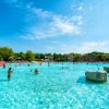 Ampia piscina con persone che nuotano, cielo azzurro sullo sfondo.