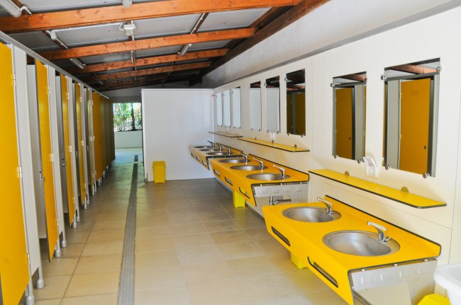 Bagno con cabine a destra e lavandini con specchi a sinistra, colorati di giallo brillante.
