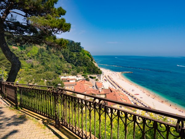 Spiaggia e mare blu visti da un balcone sopraelevato.