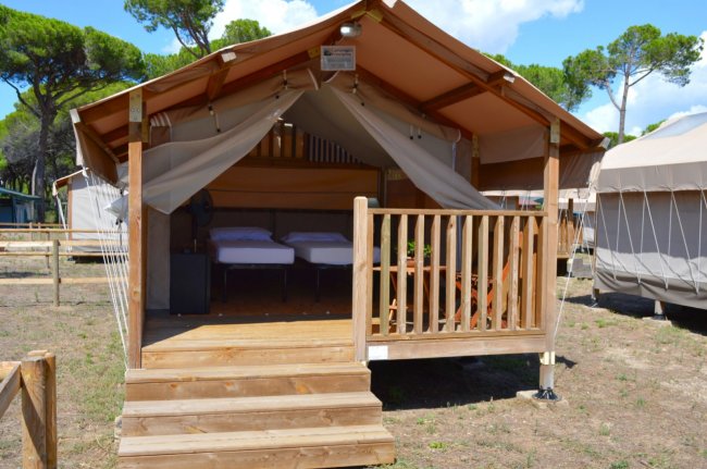 Tenda safari in legno con veranda e letti all'interno.