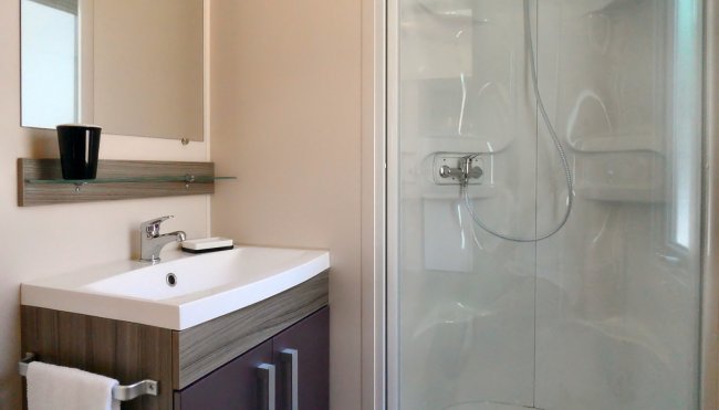 Bagno moderno con lavandino, mobile sottostante, specchio e cabina doccia.