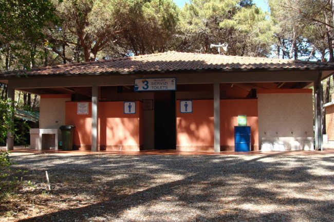 Edificio di servizi igienici in un campeggio, con ingresso e icone di toilette.