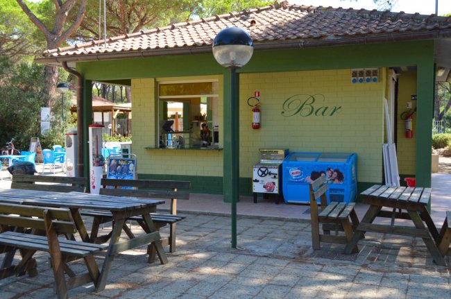 Bar all'aperto con tavoli di legno e distributore di gelati.