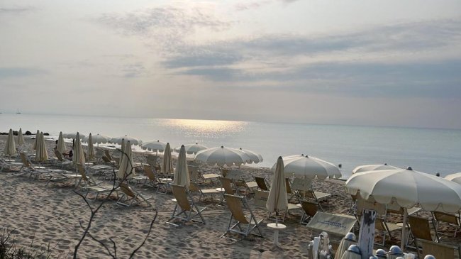 Spiaggia con ombrelloni e lettini al tramonto.