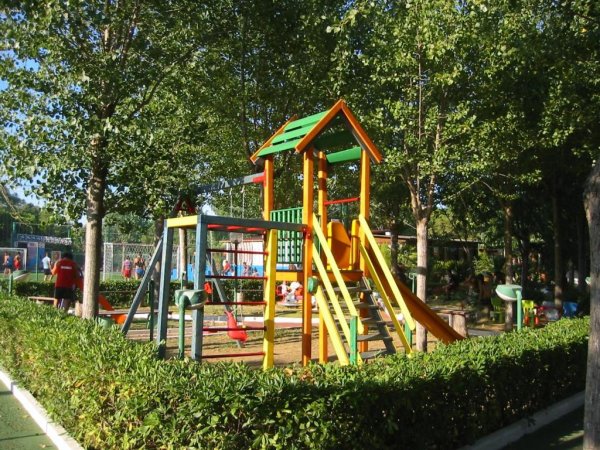 Area giochi con struttura colorata e alberi.
