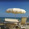 Due lettini e ombrellone bianco su una spiaggia con mare blu.
