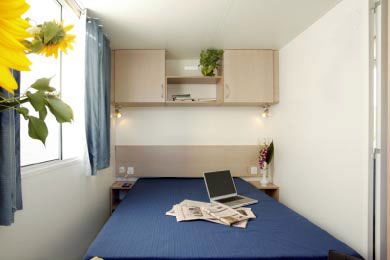 Camera da letto con letto matrimoniale, un laptop e giornali sul letto.