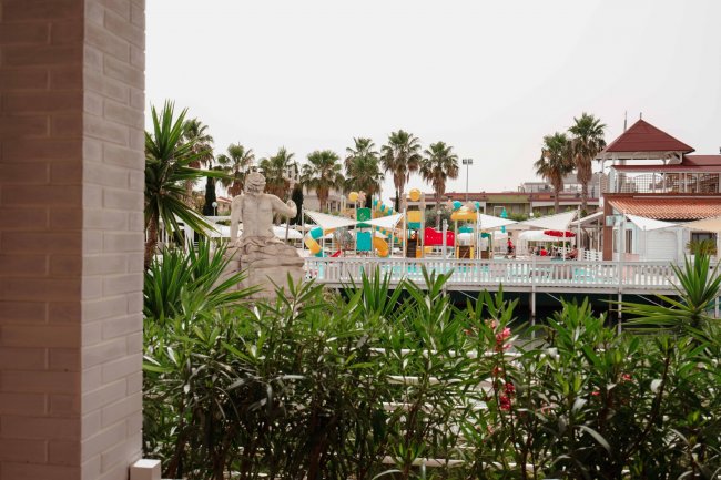 Area giochi acquatica con palme e statue.
