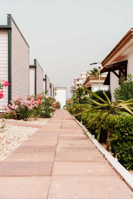 Sentiero tra bungalow fiancheggiato da fiori e arbusti.