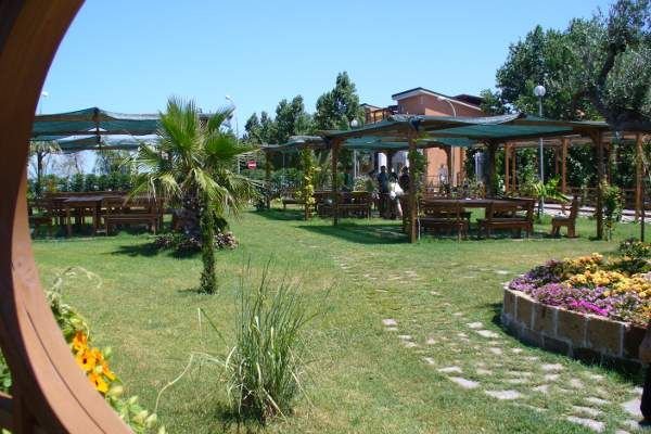 Giardino con tavoli e piante verdi, percorso di pietre.