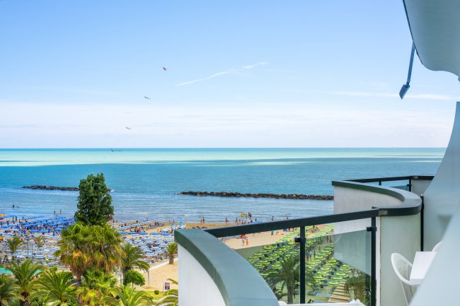 Vista mare da un balcone, con spiaggia e ombrelloni.