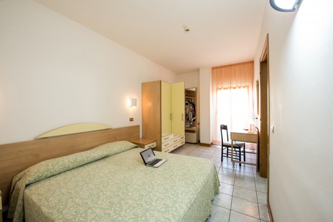 Camera da letto con letto matrimoniale, scrivania e armadio aperto.