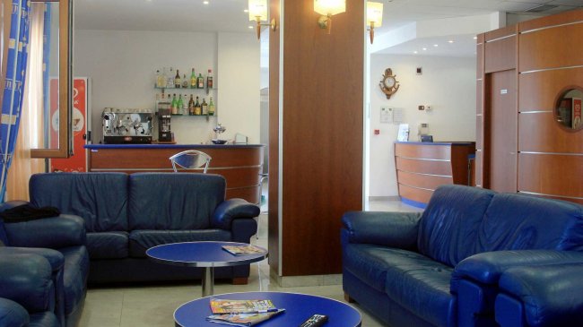 Salotto con divani blu e tavolini rotondi.