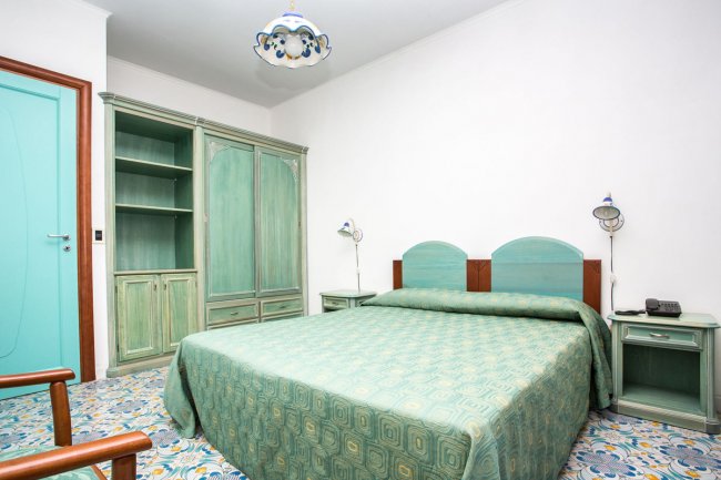 Camera da letto con mobili in legno verde e copriletto coordinato.