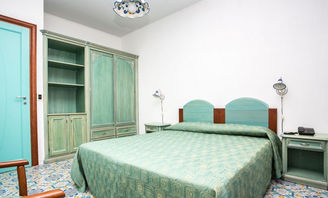 Letto matrimoniale verde con armadio e porte turchesi.