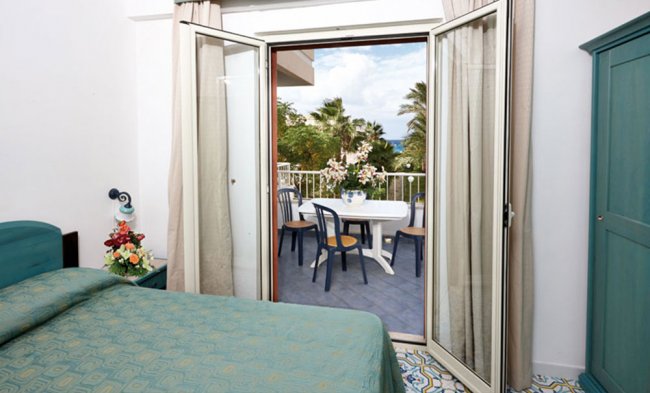 Camera con letto matrimoniale e terrazza con vista mare.