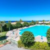 Ampia piscina all'aperto con lettini, vista mare.