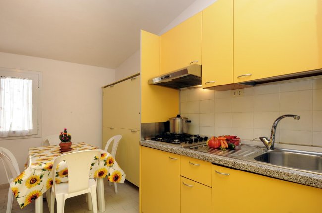 Cucina con mobili gialli e tavolo fiorito.