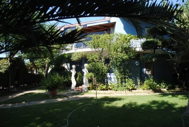 Casa blu con giardino e statue.
