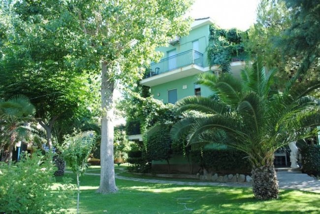 Casa verde tra alberi e palme.