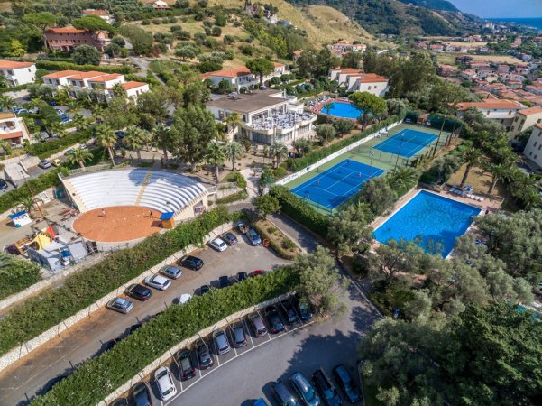 Complesso con campi da tennis, piscina e anfiteatro all'aperto circondato da colline e case.