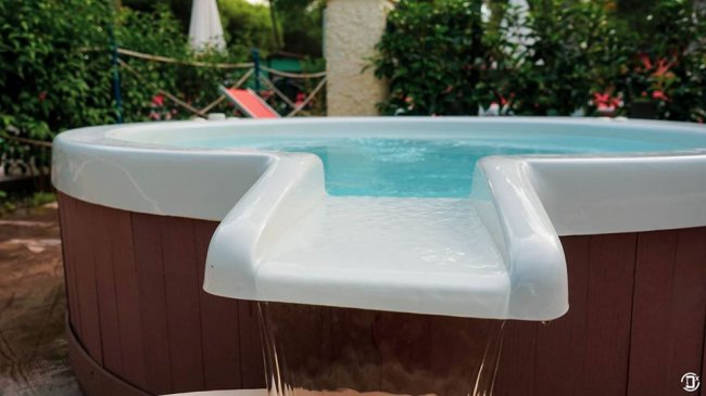 Vasca idromassaggio con acqua che trabocca in un giardino.