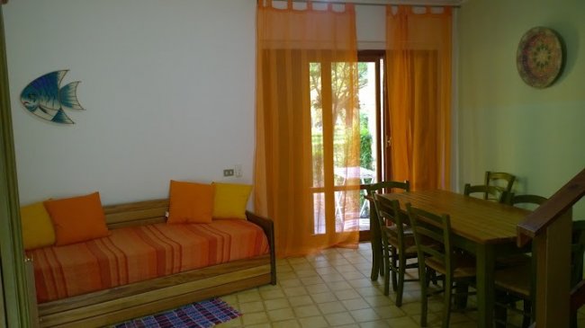 Sala con divano arancione e tavolo da pranzo vicino alla finestra.