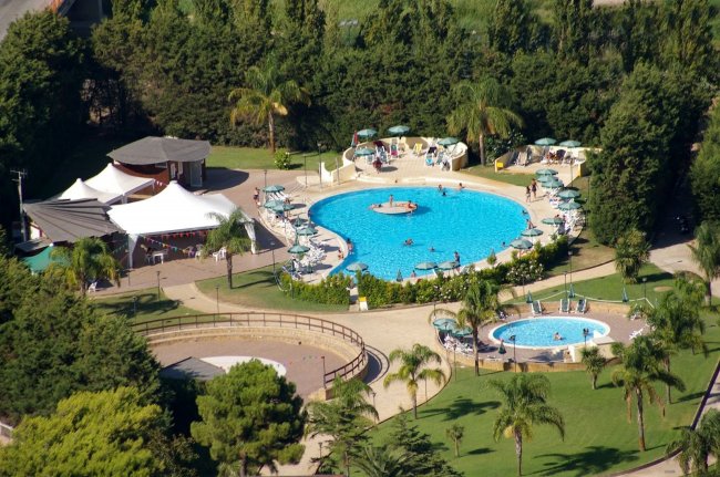 Vista dall'alto di due piscine in un giardino con alberi.