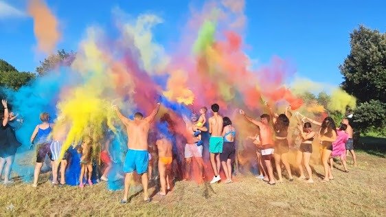 Festa all'aperto con polveri colorate lanciate in aria.