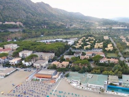 Veduta aerea di un paese costiero con montagne sullo sfondo.