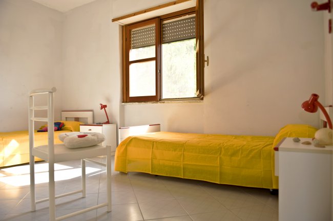Una camera da letto con due letti singoli gialli e una finestra.
