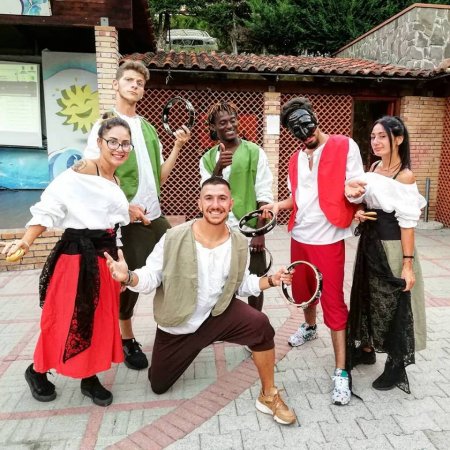 Gruppo di sei persone in costumi tradizionali, alcuni con tamburelli.