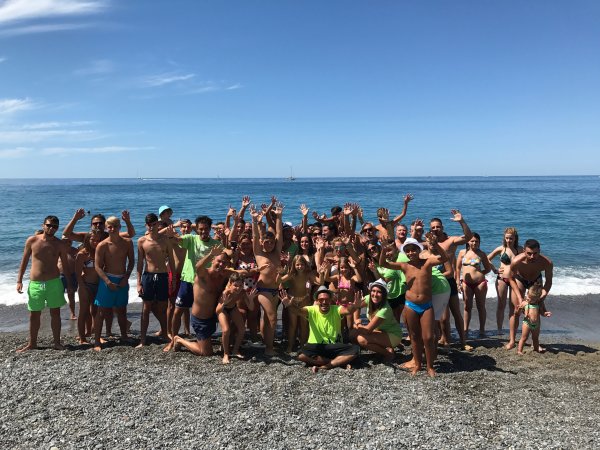 Gruppo di persone sulla spiaggia che festeggiano davanti al mare.