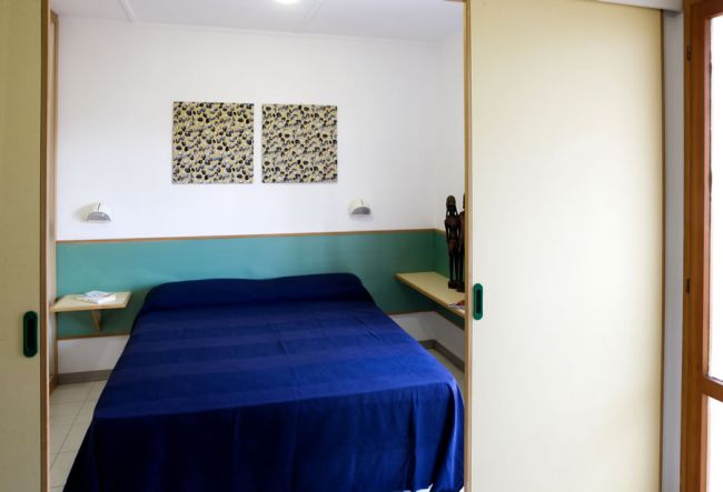Una camera con letto matrimoniale, coperte blu e opere d'arte sulle pareti.