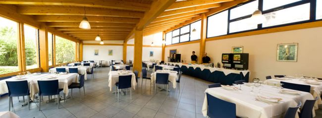 Ristorante luminoso con tavoli apparecchiati e sedie blu.