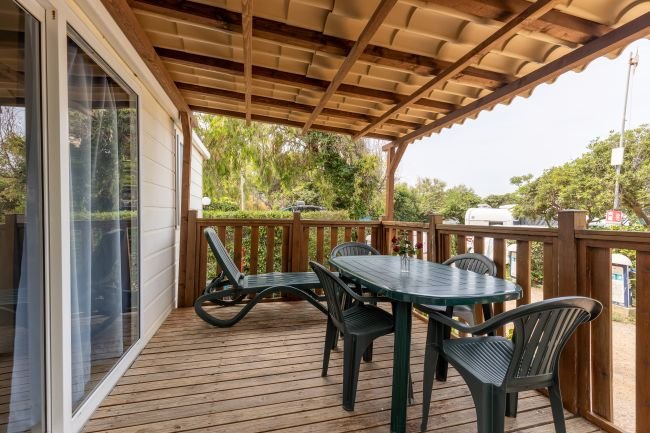 Veranda coperta con tavolo e sedie in plastica verde.