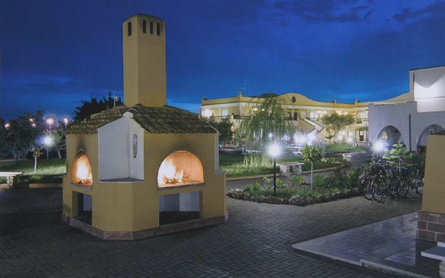 Forno esterno con camini accesi in un cortile illuminato di notte.